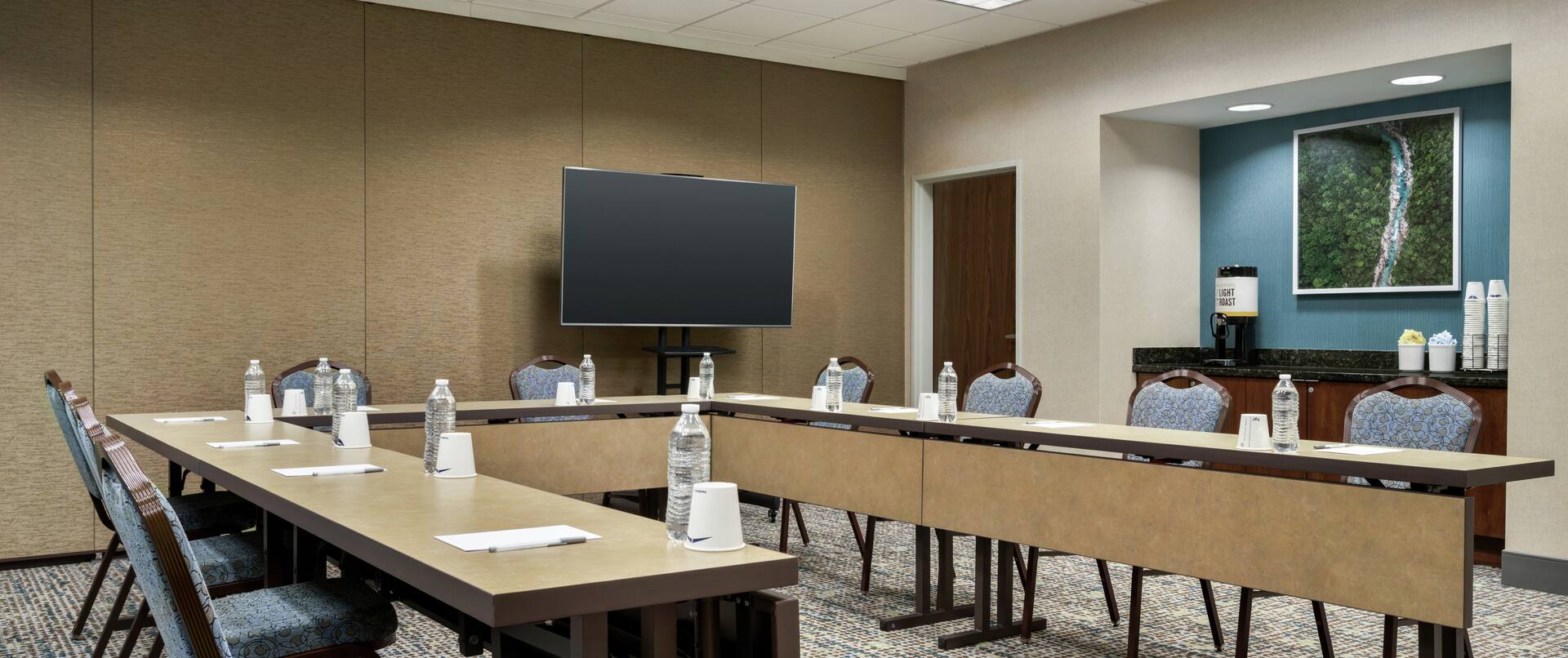Convenient on-site meeting space featuring u-shape setup, TV at front of room, and coffee break station.