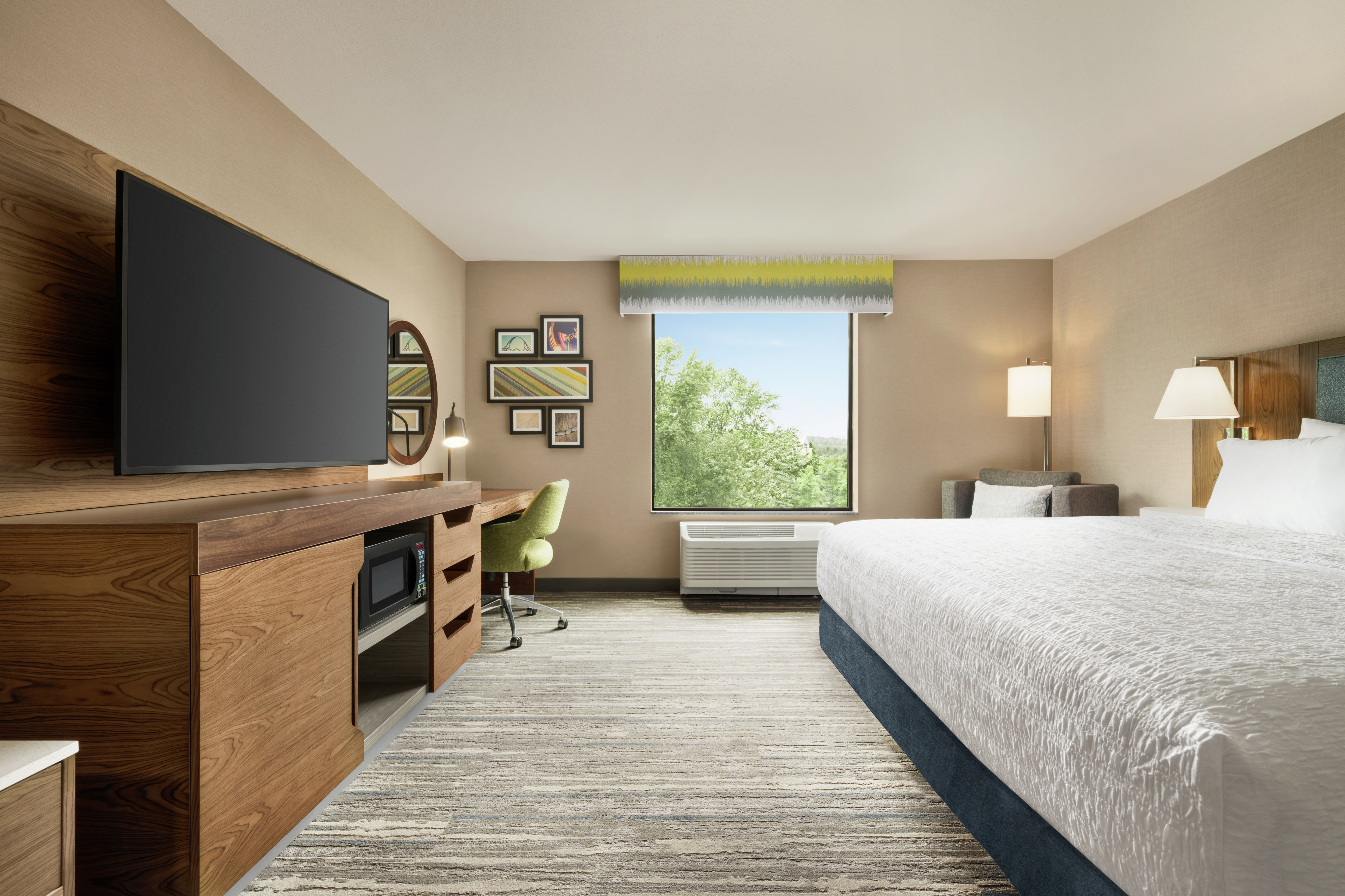 Spacious guest room featuring comfortable king bed, work desk, and stunning outside view.