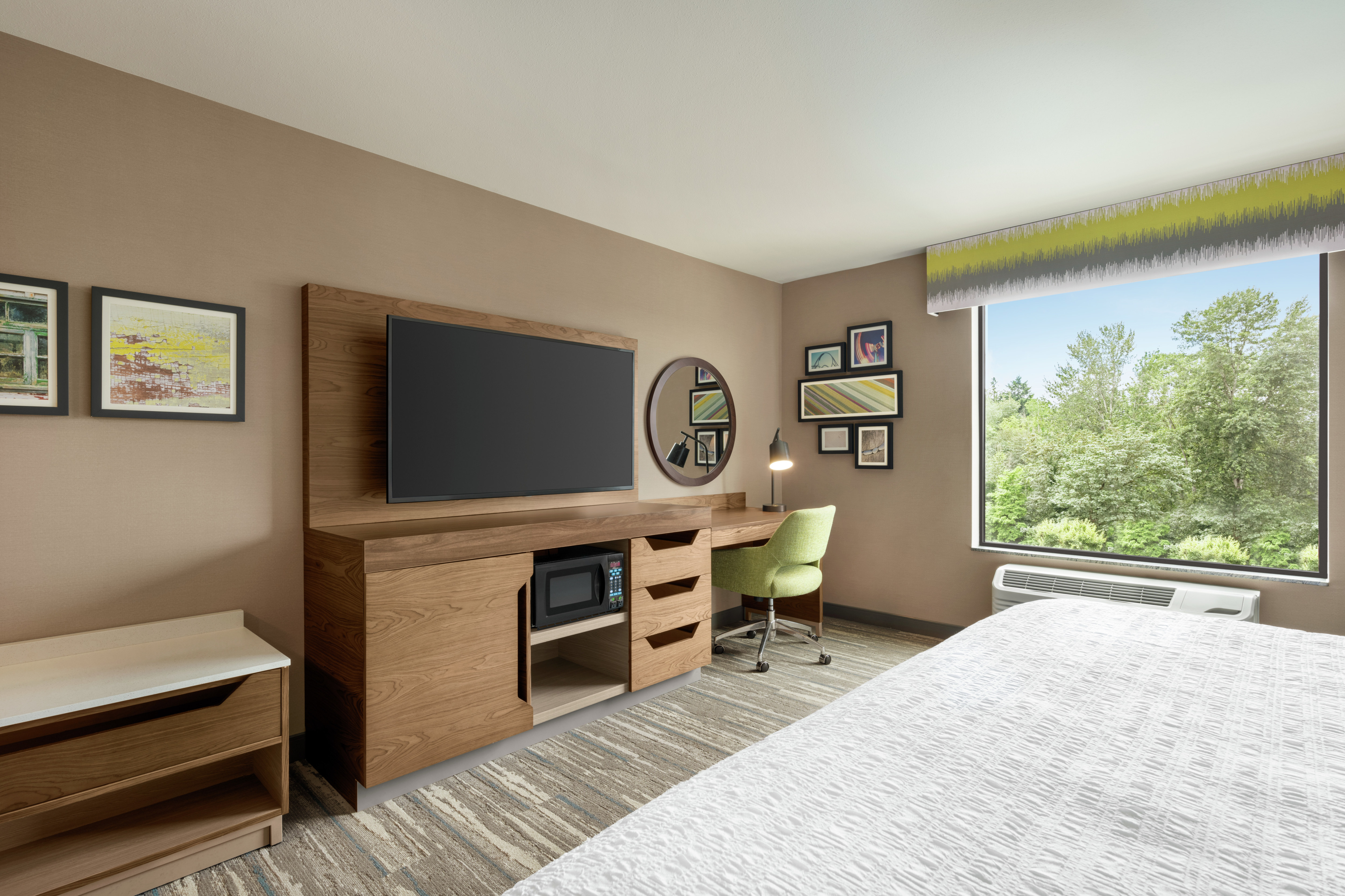 Spacious guest room featuring work desk, TV, comfortable king bed, and stunning outside view.