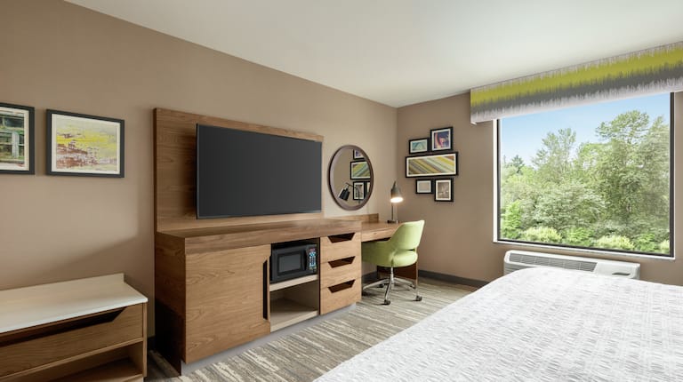 Spacious guest room featuring work desk, TV, comfortable king bed, and stunning outside view.