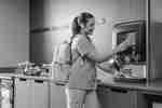 woman making takeaway coffee in machine 
