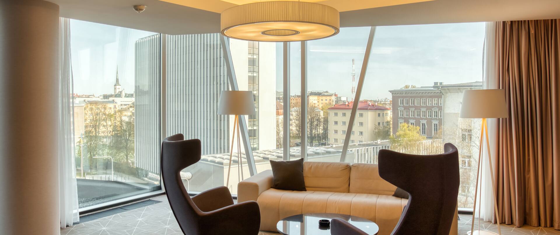 Loungebereich der Suite, Sofa, Kaffeetisch, Stühle, Stadtblick aus dem Fenster