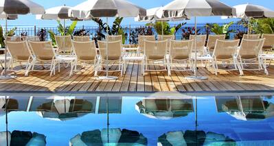 Outdoor Swimming Pool Area with Deck Chairs and Umbrellas at Daytime