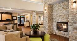 Soft Seating Around Fireplace in Lobby Lounge Area With View of Front Desk and Snack Shop