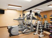 Fitness Center With TV. Cardio Equipment by Mirrored Wall, Free Weights, and Weight Balls