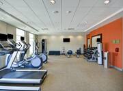 Spin2Cycle Fitness Area With Cardio Equipment Facing Windows, Weight Machine, TV, Weight Benches, Blue Exercise Ball, Weight Balls, Large Mirrors, Free Weights, and Water Cooler