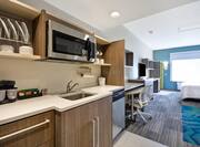Studio Suite Kitchen With Dishes in Cabinets, Microwave Above Sink, Dishwasher, and Microwave