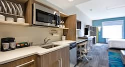 Studio Suite Kitchen With Dishes in Cabinets, Microwave Above Sink, Dishwasher, and Microwave