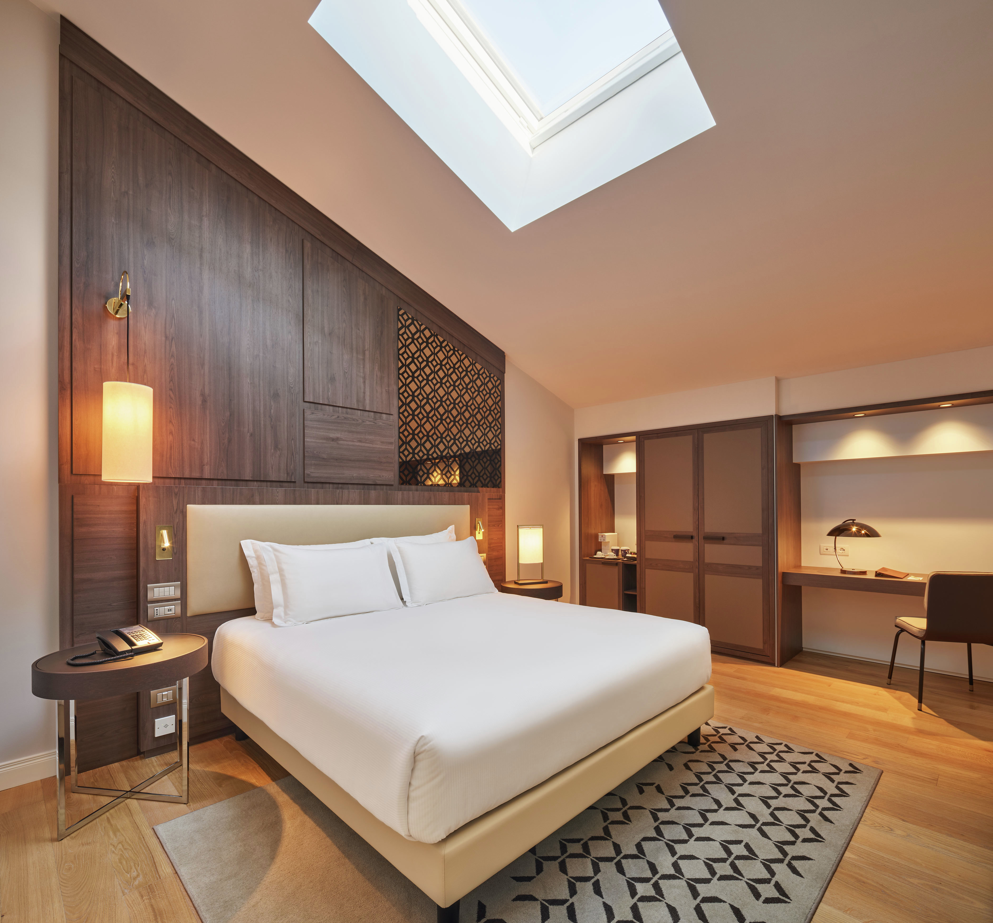 a bed in a room with vaulted ceiling and a skylight
