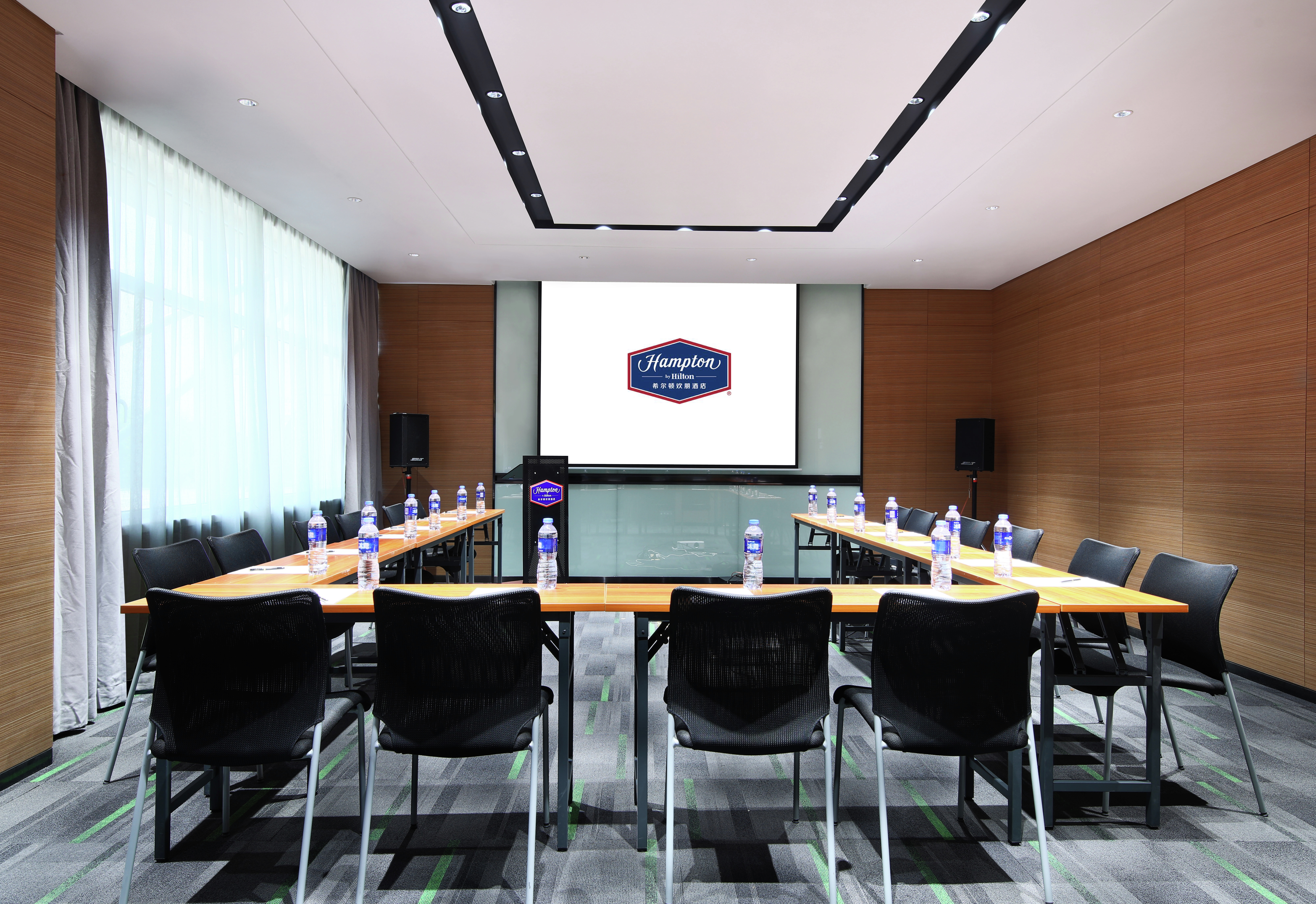 Meeting Room with Projector Screen, Floorstanding Speakers, and Table and Chairs in U-Shaped Setup