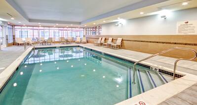 Indoor Pool Surrounded by Windows, Chairs, Tables, and Loungers 