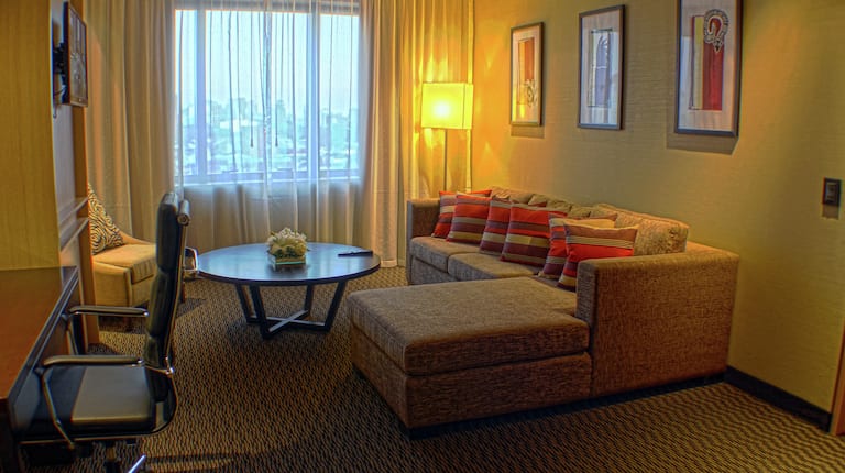 Área de lounge de la suite con sofá, escritorio y televisor