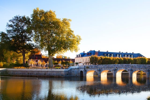 Hotel exterior with bridge crossing river and trees