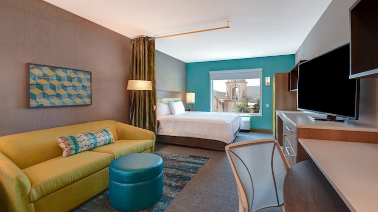 guest room lounge area with bed window television and work desk