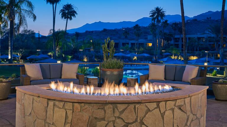 Sunset View of Firepit on Patio with Lounge Chairs and Mountains in the Background