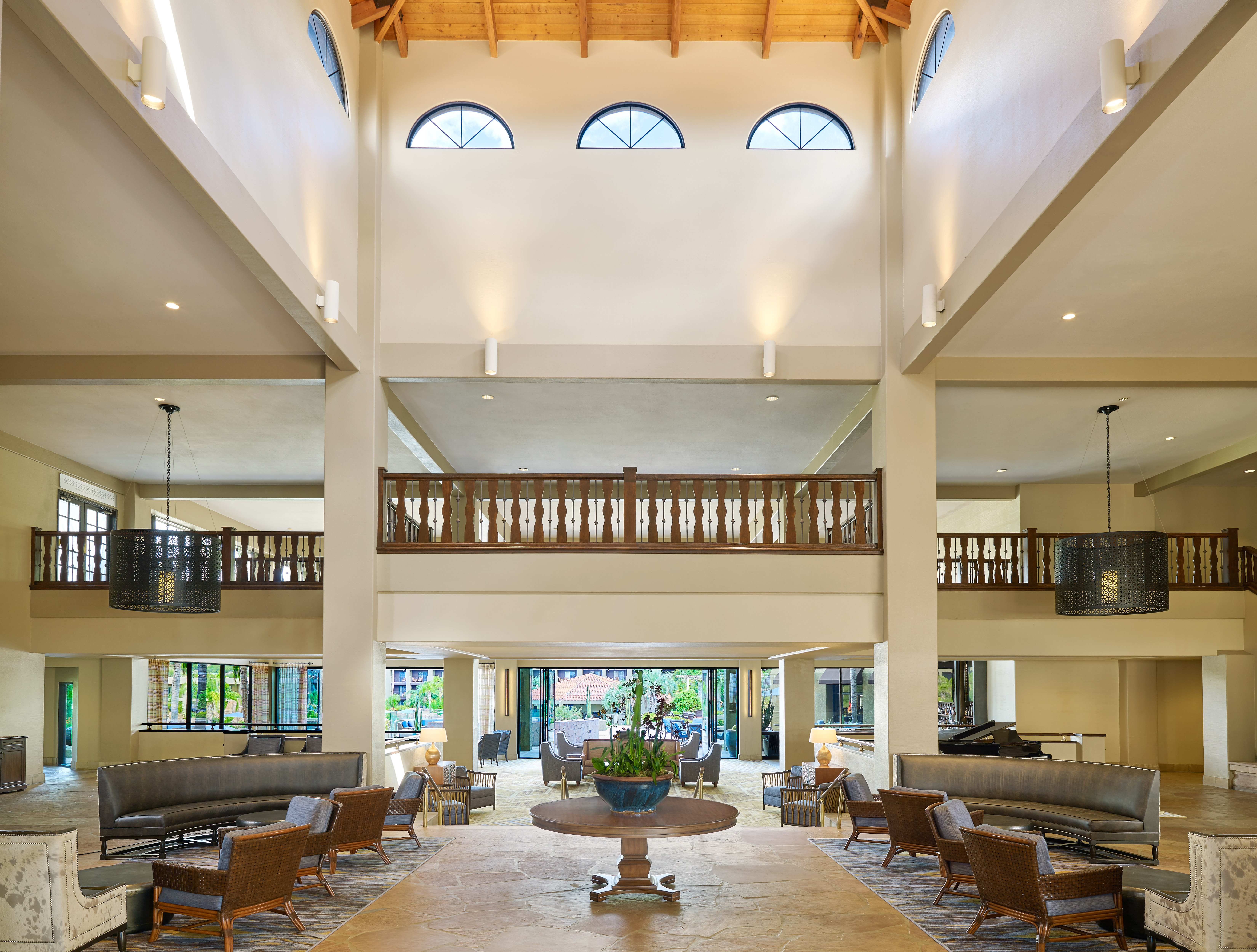 Grand View of Lobby Seating Area with Large Round Table in the Center Surrounded by Sofas and Chairs and Views of Upstairs and Outside