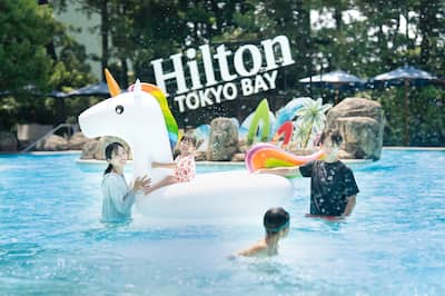 Family in pool at daytime with unicorn floating device