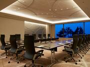 Cyan Meeting Room With U-Shaped Table and Chairs Facing Large Window With Open Drapes to Night View