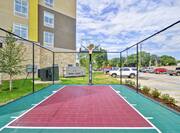 Outdoor Multi-Purpose Sport Court With Basketball Goal and Parking Lot in Background