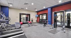 Fitness Center With Cardio Equipment, Three Large Mirrors, Two Red Exercise Balls, Weight Bench, TV, Free Weights, and Weight Machine