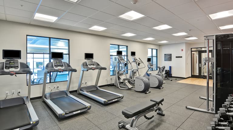 Fitness center with exercise machines, free weights, and windows