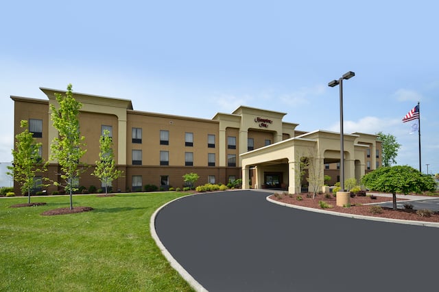 Daytime View of Hotel Exterior, Signage, Flagpole, Landscaping, Porte Cochère, and Parking Lot