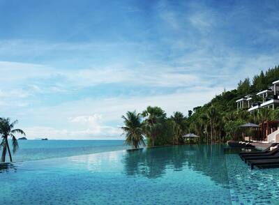  A private infinity pool looking out to the ocean with palm trees and villas in the background.