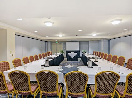 Meeting room with U-shaped table, chairs, and presentation screen