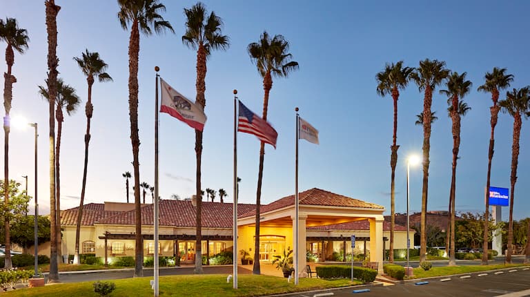 Hotel Exterior at Dusk with Palm Trees and Flags