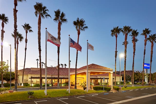 Hotel Exterior at Dusk with Palm Trees and Flags