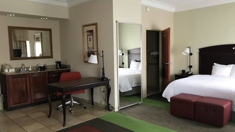Guest suite with bed, wet bar area, work desk and chair.
