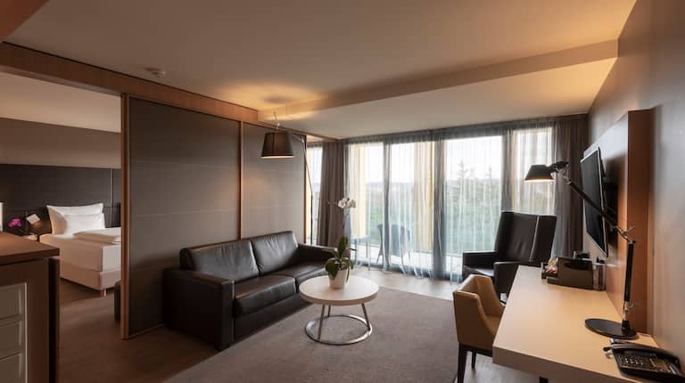 Loungebereich der Suite mit Sofa, Stuhl, Schreibtisch und wandmontiertem Fernseher