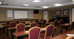 Classroom Setup in Meeting Room With Tables and Chairs Facing Presentation Screen