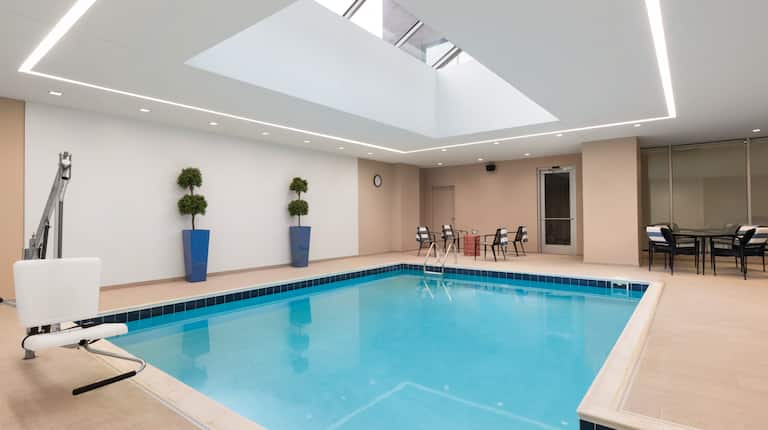 Tables and Chairs Around Indoor Pool With SkylightIndoor Pool with Lounge Chairs