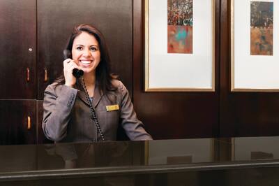 Smiling Receptionist on the phone at the Front Desk.