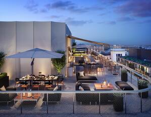 View of Rooftop Bar with Dining Tables, Chairs, and Soft Seating at Dusk