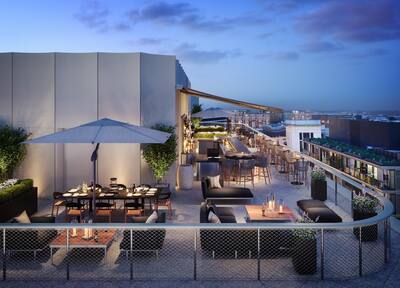 View of Rooftop Bar with Dining Tables, Chairs, and Soft Seating at Dusk