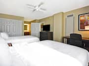 Two Queen Beds, Ceiling Fan, Opening to Brightly Lit Vanity Mirror, Open Doorway to Kitchen, TV, Work Desk and Wall Art