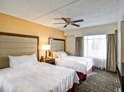Spacious Guest Room With Double Queen Beds, Bedside Table With Lamp, Ceiling Fan, Large Window, and TV