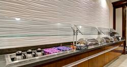 Angled View of Breakfast Buffet With Milk, Yogurt, Condiments, Hot Food Selections and Utensils