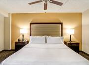 King Bed, and Bedside Tables With Brightly Lit Lamps and Ceiling Fan