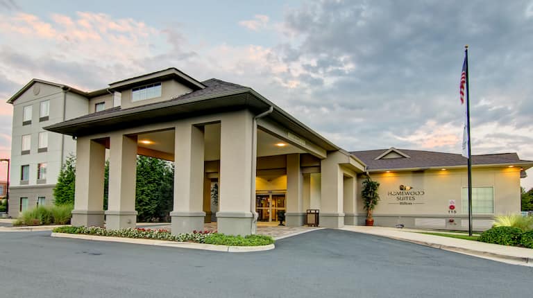 Illuminated Hotel Exterior, Signage, Circle Drive, Flag Pole, and Landscaping at Dusk