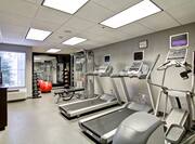 Fitness Center With Free Weights, Red  Exercise Ball, Mirrored Wall, Weight Balls, Bench, and Cardio Equipment