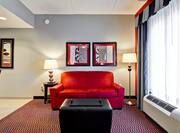 Red Sofa Bed, Black Ottoman, Lamps, Wall Art by Window
