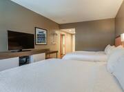 Two white beds in a hotel room with TV