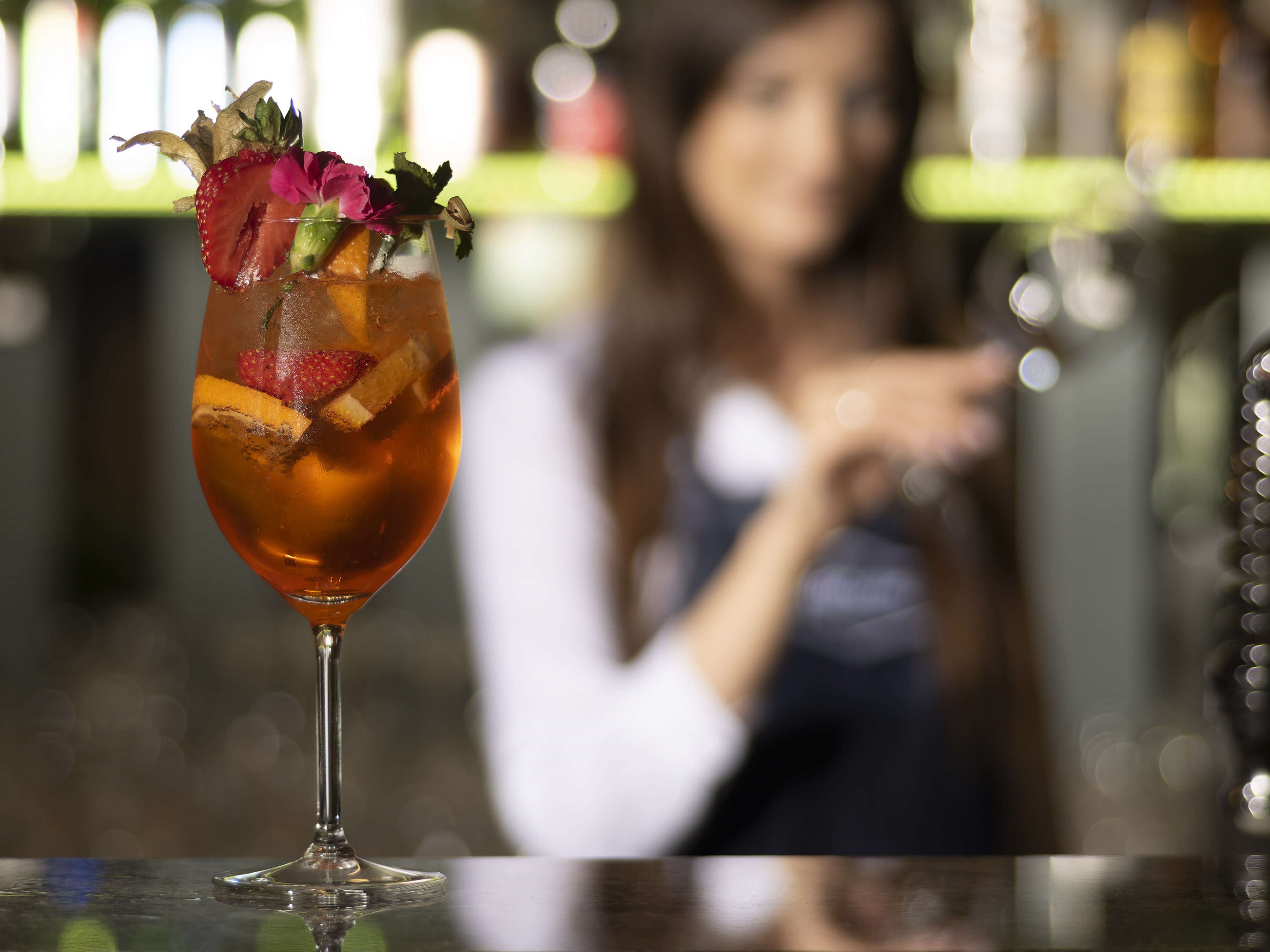 Woman Enjoying a Drink with Fruits at a Bar