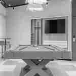 Lobi oyun alanında masalar ve sandalyeler bulunan bir havuz masası ve duvara monte geniş bir TV.