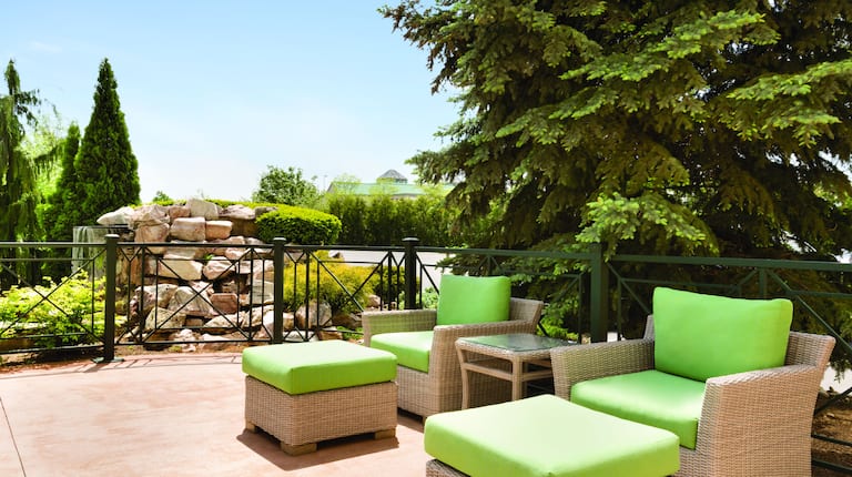 Chaises et poufs avec coussins verts sur le patio extérieur