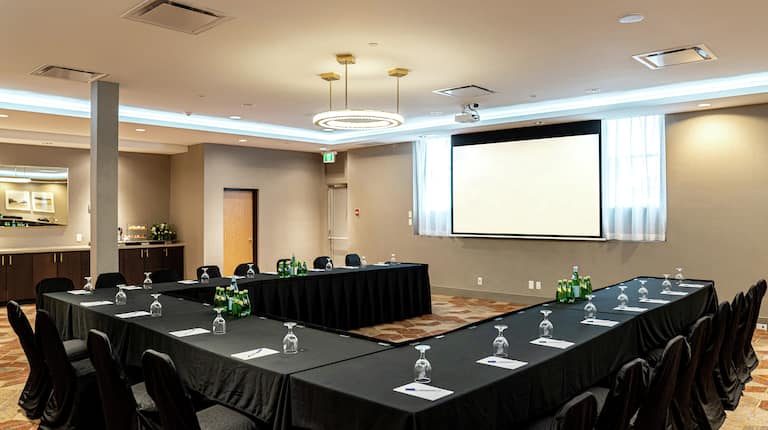 a u-shaped meeting table and a presentation screen in a room
