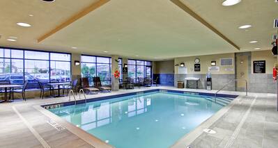 Indoor Pool With Tables, Chairs, Loungers, Windows, and Water Cooler
